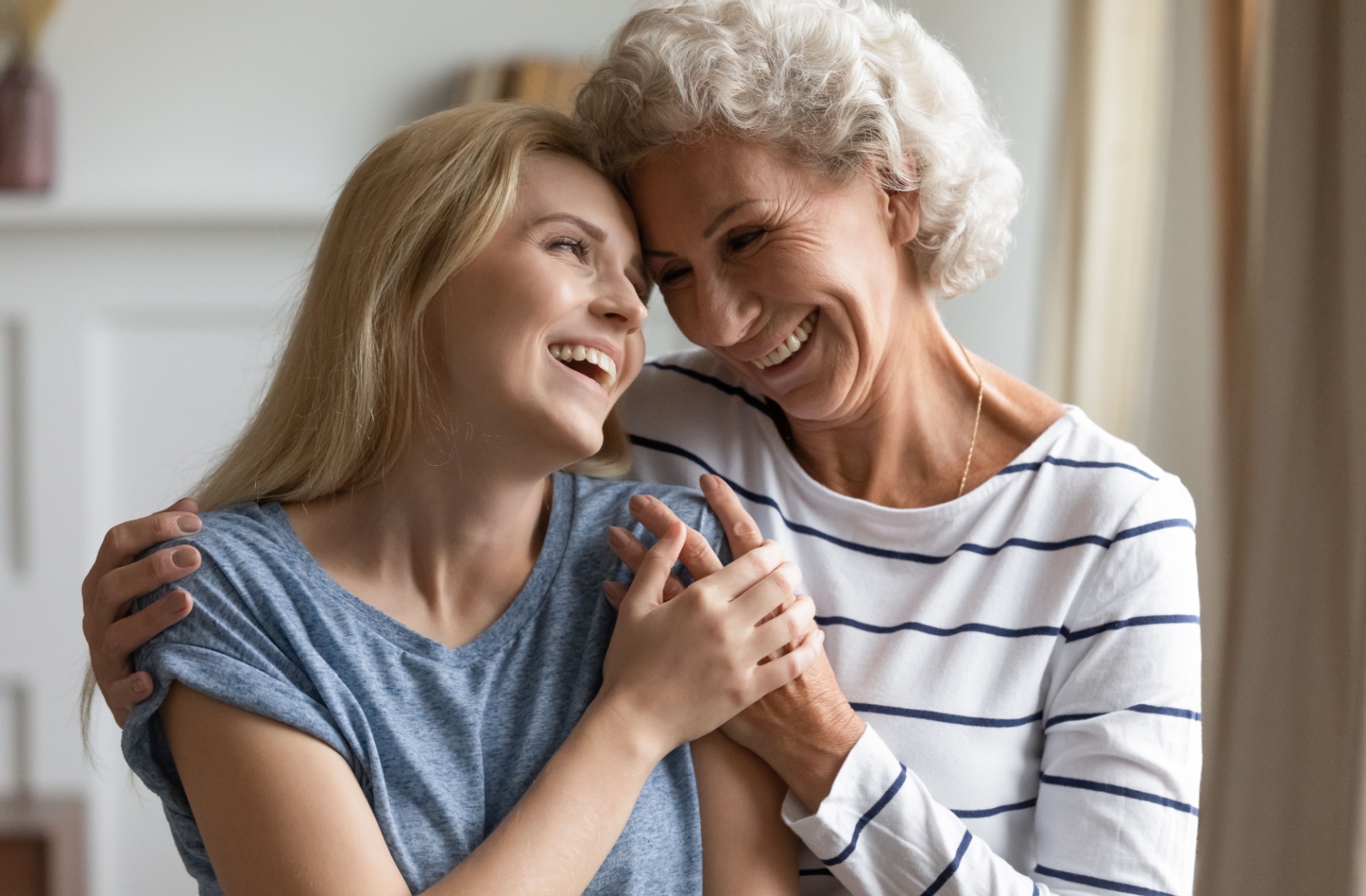 An older woman and her daughter smiling at each other while they hold hands.