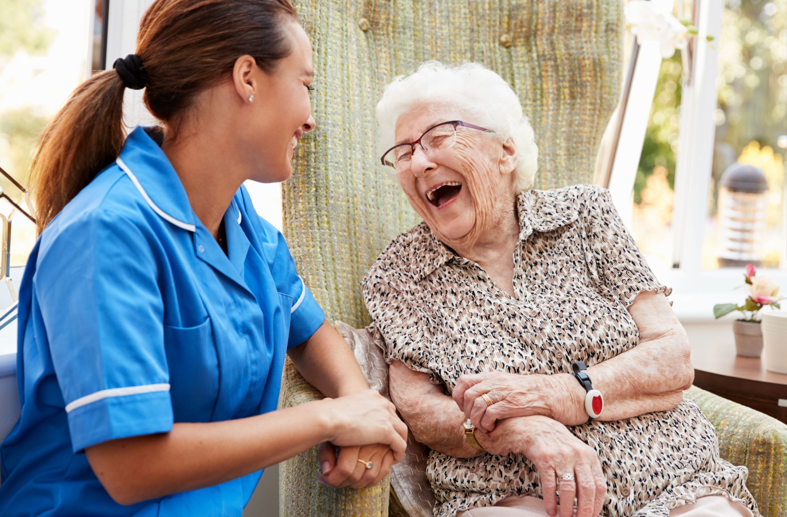 A senior woman and her caregiver laughing together in memory care.