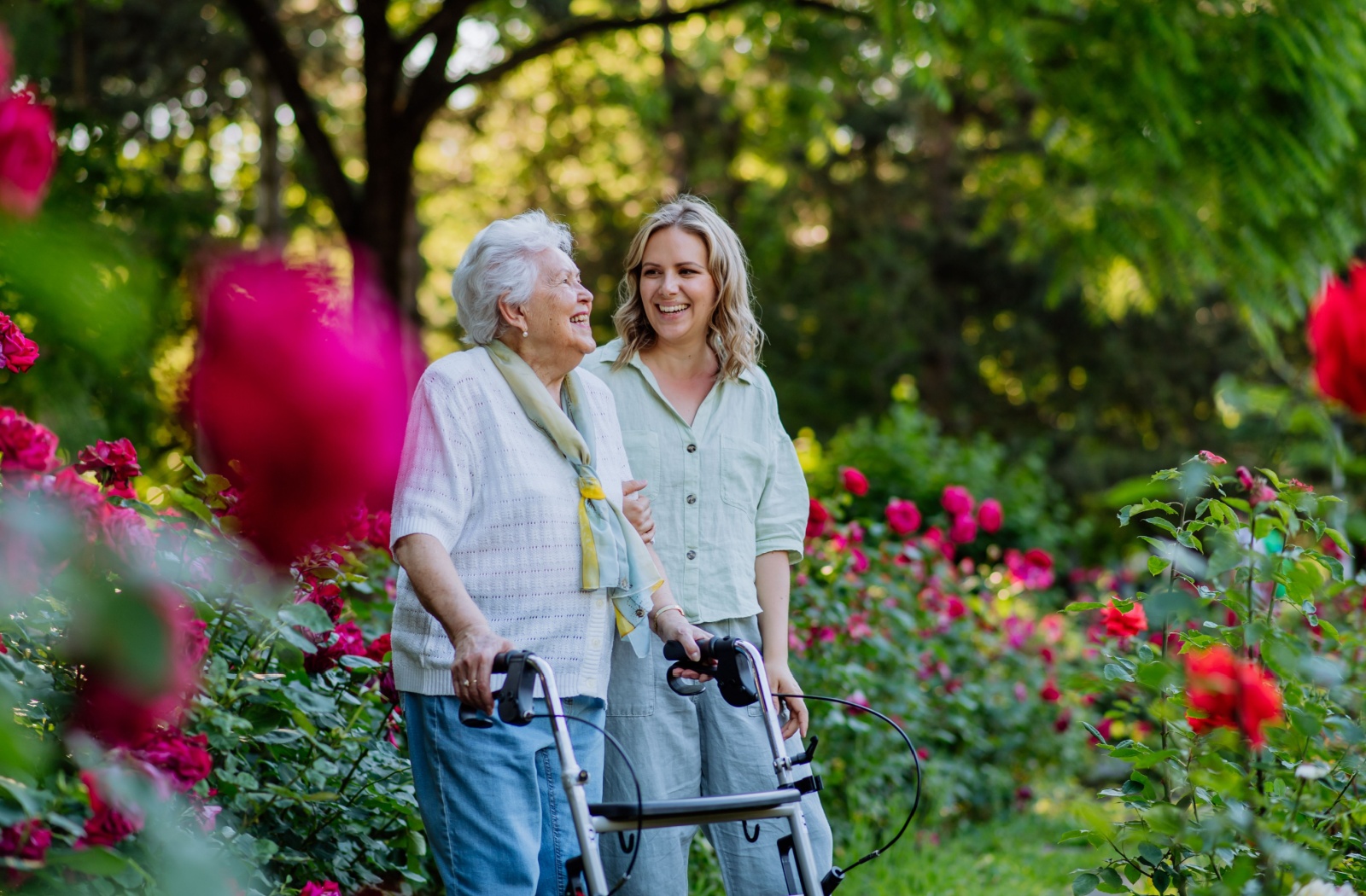 A senior and their adult child talking a walk through the garden