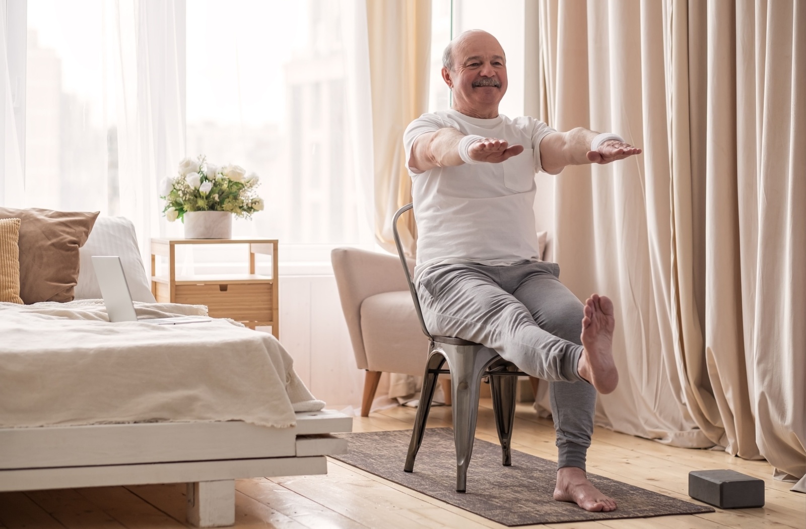 A senior practices chair yoga in their room.