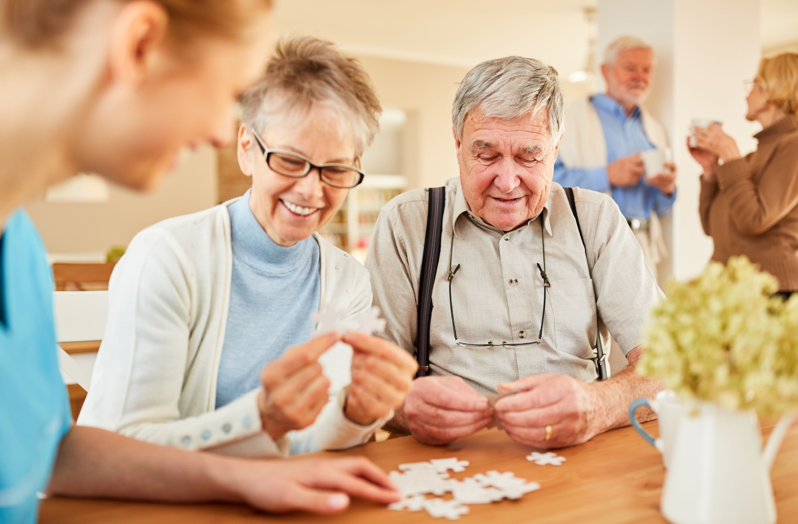 A group of older adults with dementia in memory care laughing while working together to finish a puzzle activity.