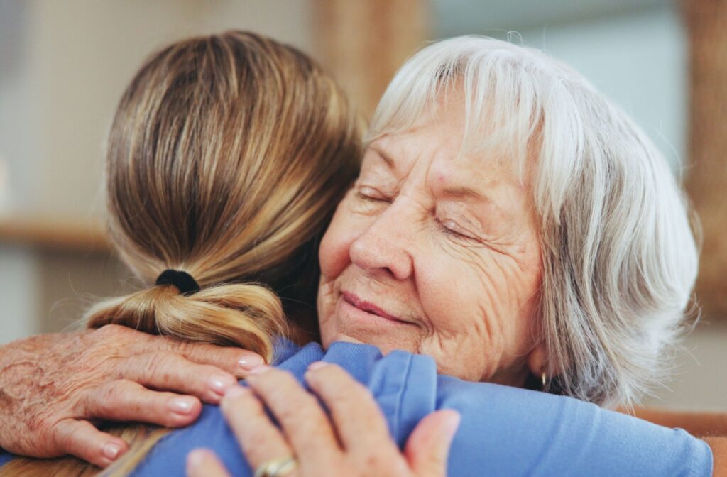 An appreciative older adult hugs their caregiver after getting some support with their daily routine